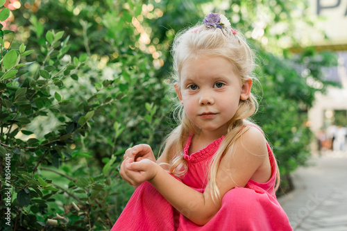 Little child girl portrait with blue eyes looking at the camera in summer yard. Copy space and empty place for advertising. Childhood and preschooler concept