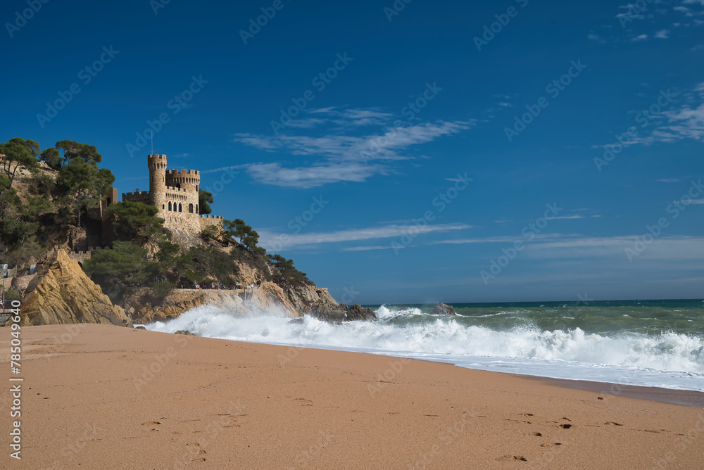 Lloret de Mar Castell on the beach of Sa Caleta, with a strong swell and white waves that reach the sand. Costa daurada, Catalonia Spain. Summer vacations 