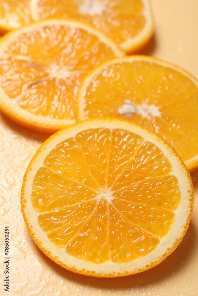Fototapeta premium Slices of juicy orange and water on beige background, closeup