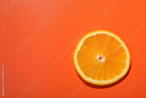 Slice of juicy orange on terracotta background  top view. Space for text