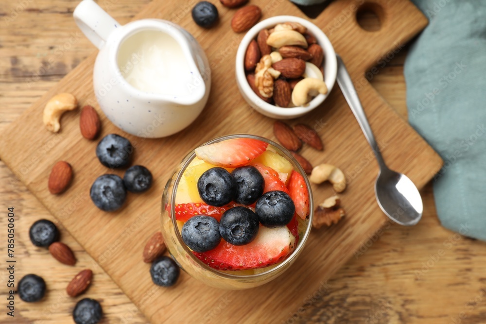 Delicious fruit salad, berries and nuts on wooden table, flat lay Delicious fruit salad, berries and nuts on wooden table, flat lay