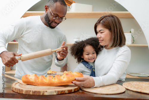 Happy multiethnic family mother father and child having fun playing in cozy kitchen together at home. Playful biracial daughter embracing bonding with dad and Asian mom. Diverse of multiracial people