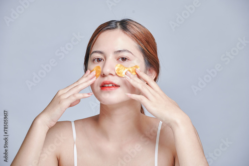happy modern female with eye patches isolated grey background..attractive woman applying anti-fatigue under-eye mask. Skin care girl touch patches of fabric mask under eyes to reduce eye bags.