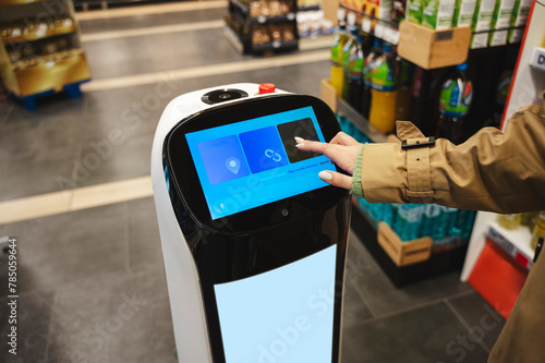 Woman interacting with robotic assistant at supermarket photo