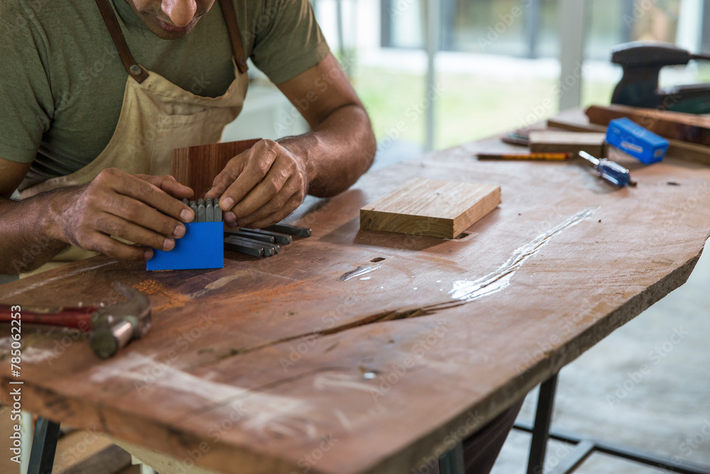 Carpenter using steel punch tool kit at workbench in woodshop
