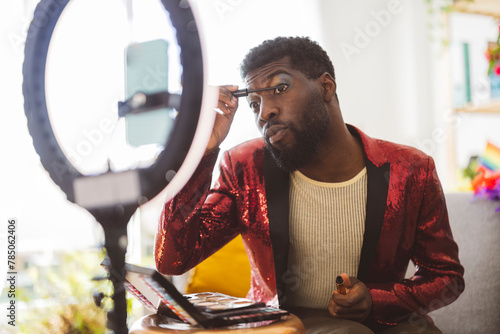 Non-binary person doing eye make-up near ring light at home photo
