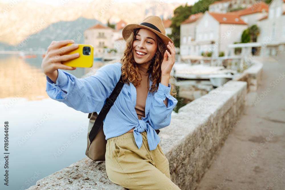 Young female tourist is exploring new city making photo on smartphone. Selfie time. Lifestyle, adventure, nature, active life.