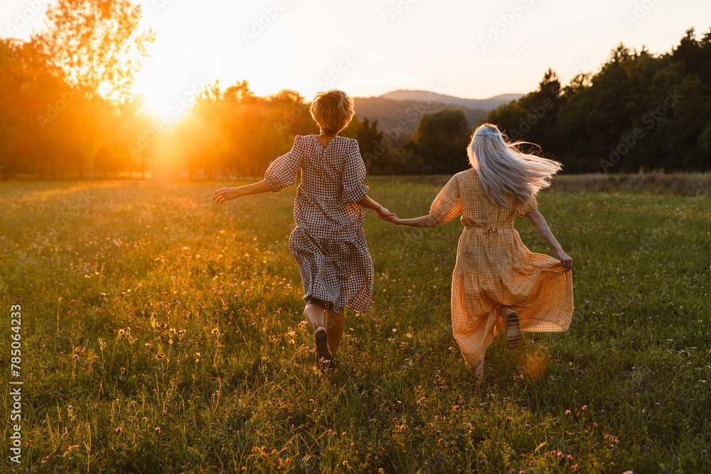 Friends holding hands and running on grass in park Friends holding hands and running on grass in park