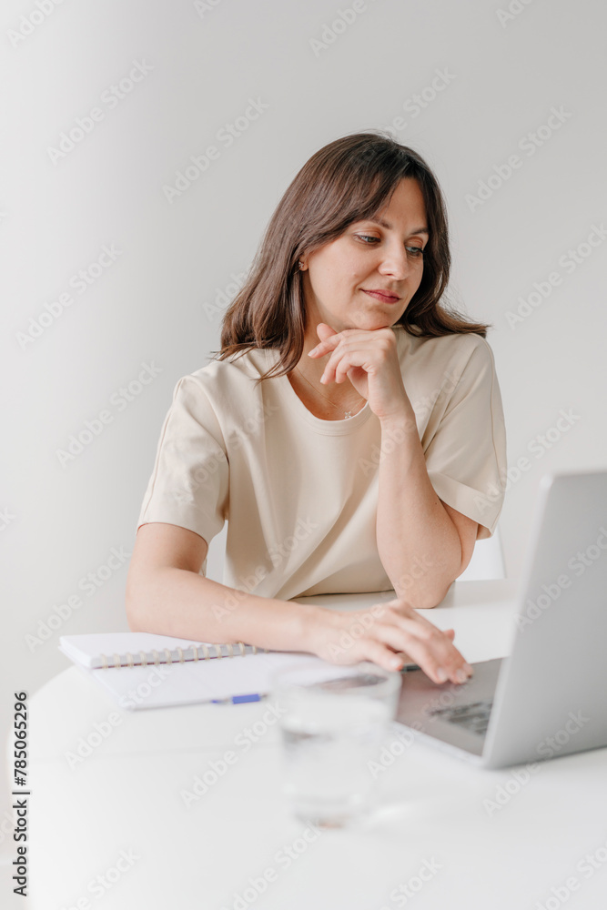 Businesswoman using laptop sitting on desk in home office Businesswoman using laptop sitting on desk in home office