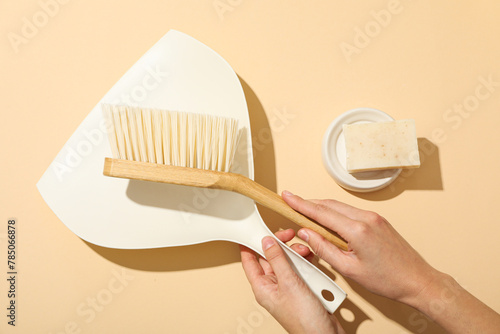 Soap and brush with scoop in hands on beige background, top view
