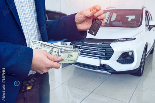 Person holding dollar money in the hands stands front car at modern showroom