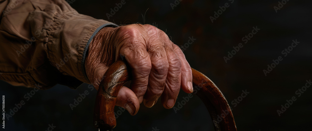 The old person wrinkled hand rests on a walking cane. A background for a boarding house for the elderly, copy space.