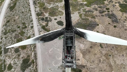 Extreme close up aerial view of a wind turbine destroyed by a fire in a arid landscape in SE Spain. Drone flying down, camera tilting up. 4K photo