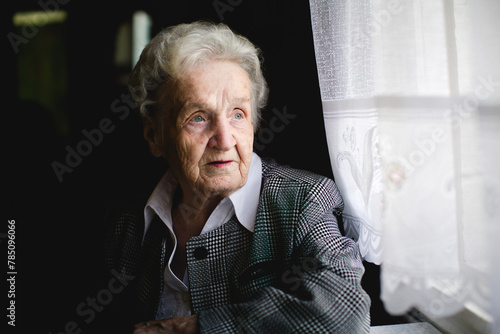 Portrait of an elderly woman in a stylish suit with an intricate woven pattern.