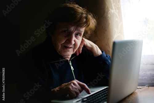 An aged woman engages with technology, her fingers tapping on a laptop keyboard. She bridges the gap between tradition and modernity, embracing the digital realm with wisdom.