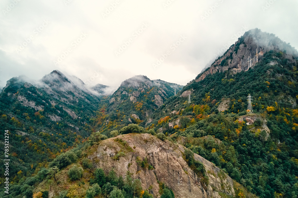 Clouds hovering above a forested mountain slope, creating a natural landscape