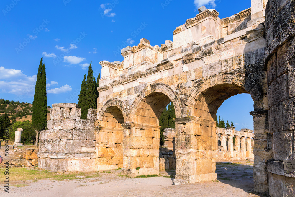 Hierapolis Frontinus Gate against blue sky and green landscape. Close up view of entrance to ancient Greek and Roman city. Pamukkale, Denizli, Turkey (Turkiye)