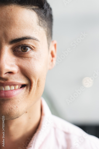 A young biracial man with brown eyes smiling in a modern business office with copy space
