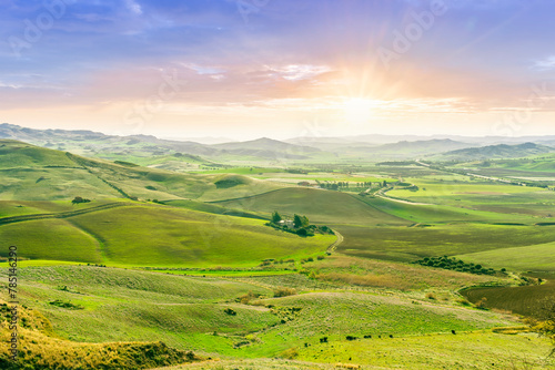 beautiful rural view at summer or spring season fields and hills with rustic grassland and nice mountains with blue cloudy sky on background of countyside landscape photo