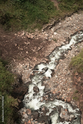 Vertical shot of a waterfall flowing through stones at Banos, Ecuador