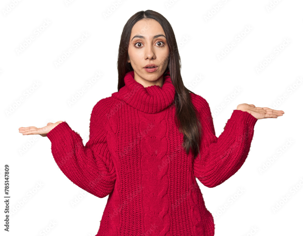 Young Caucasian woman in cozy red sweater on studio background confused and doubtful shrugging shoulders to hold a copy space. Young Caucasian woman in cozy red sweater on studio background confused and doubtful shrugging shoulders to hold a copy space.