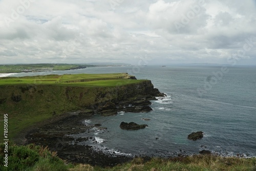 Scenic view of the sea with coastline cliffs covered with grass under the cloudy sky