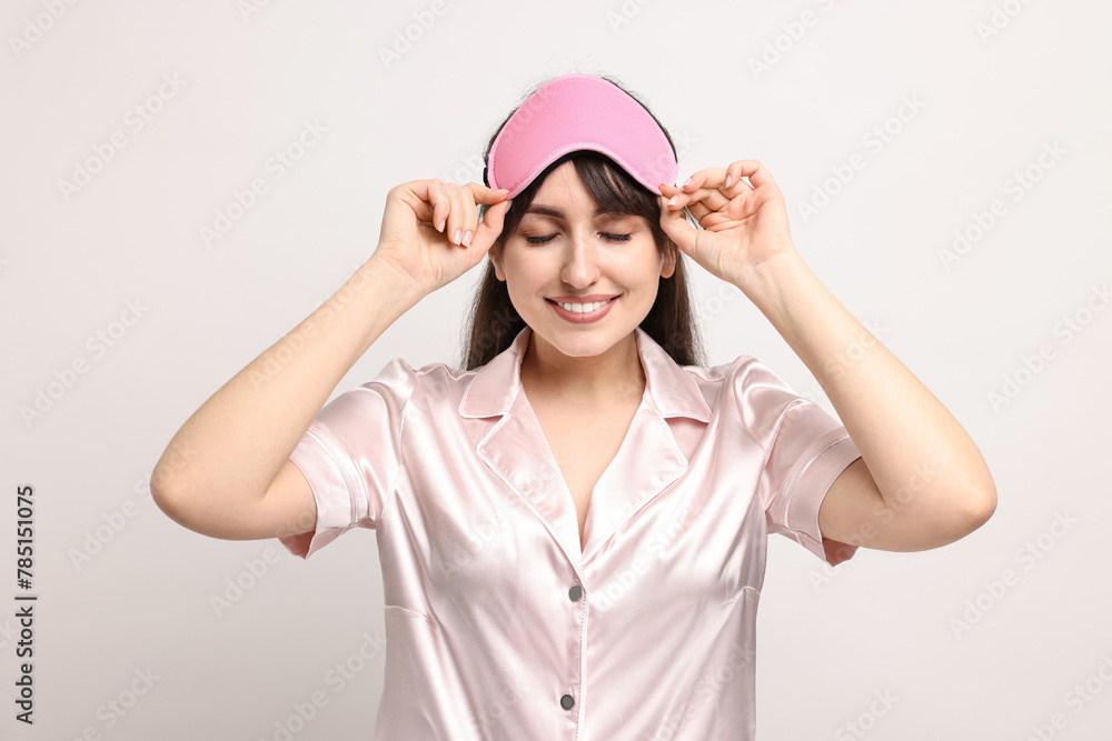 Happy woman in pyjama and sleep mask on light grey background Happy woman in pyjama and sleep mask on light grey background