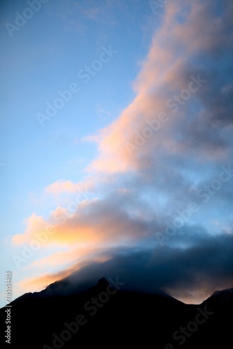 Vertical shot of clouds above mountain silhouettes during sunset