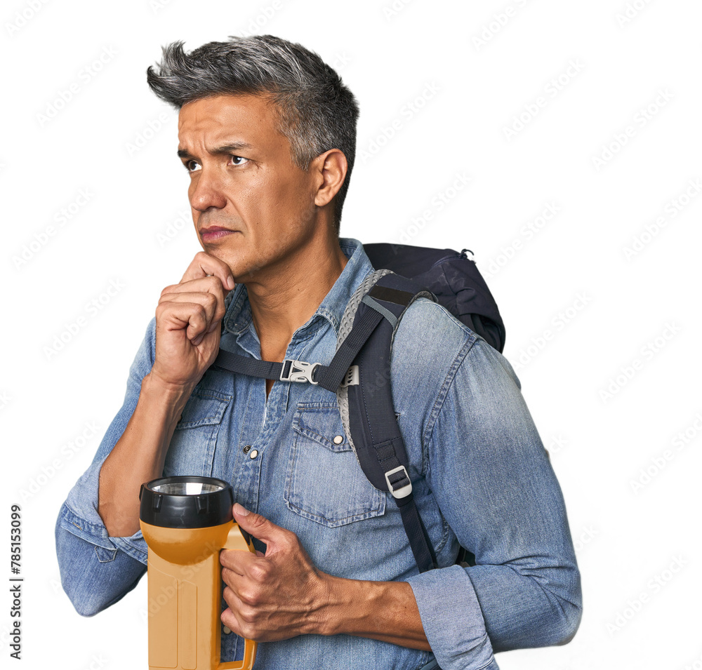 Hispanic trekker with backpack and flashlight looking sideways with doubtful and skeptical expression. Hispanic trekker with backpack and flashlight looking sideways with doubtful and skeptical expression.