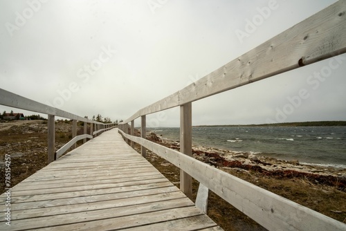 Long empty wooden walkway along the arid lakeshore under white sky