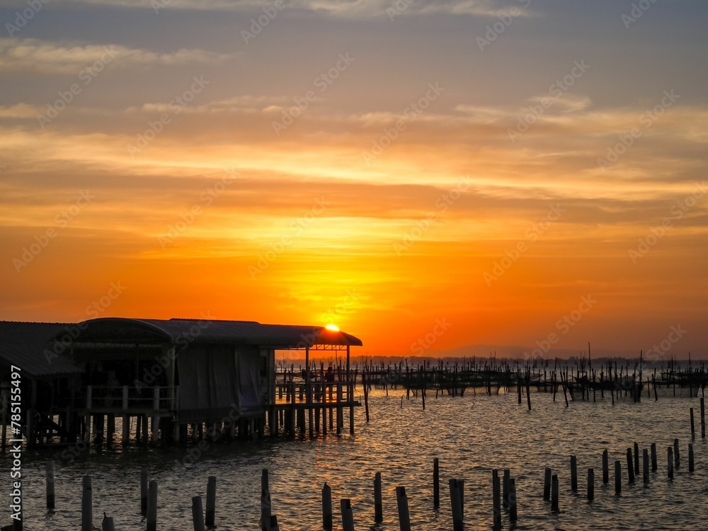 Aerial view of a bright sunset sky over wooden poles in the clear Songkhla Lake,Thailand