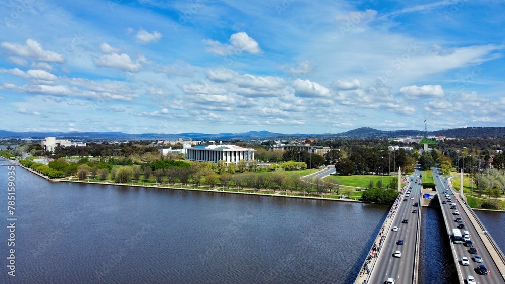 Obraz premium Bird's eye view of highways near a park and a lake under a blue cloudy sky