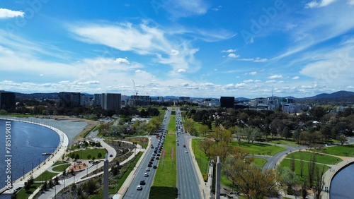Bird's eye view of highways near a park and a lake under a blue cloudy sky
