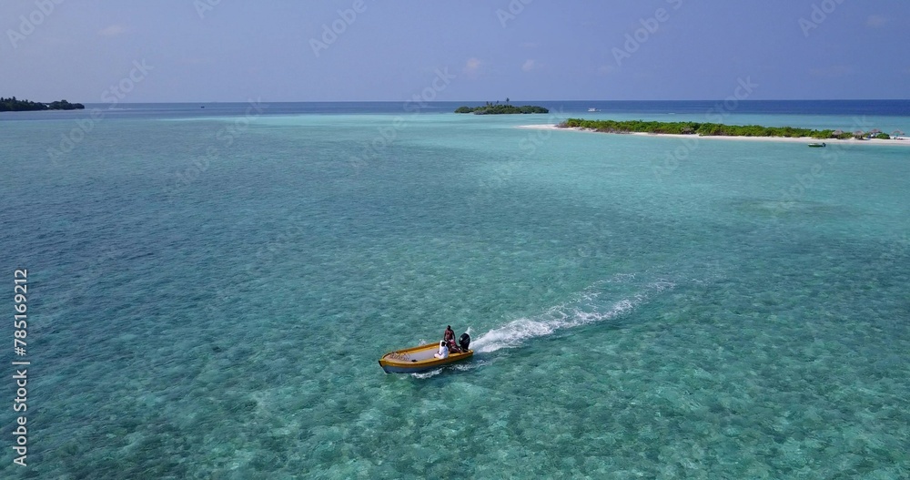 Aerial drone shot of a boat taking a tour around an island in the Maldives