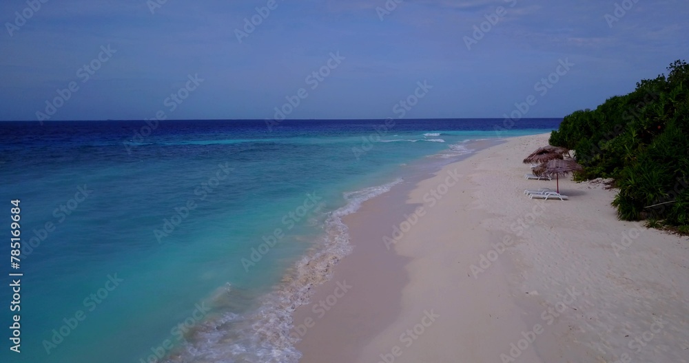 Trees, sunbeds and umbrellas on a sandy beach by the ocean Trees, sunbeds and umbrellas on a sandy beach by the ocean