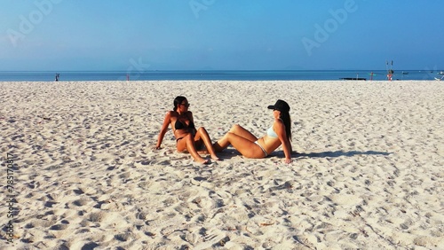 Sexy Caucasian girls with swimsuits lylng on a sandy beach with a sea view in Koh Samui, Thailand