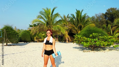 Caucasian sexy girl working out with a dumbbell on a sandy beach