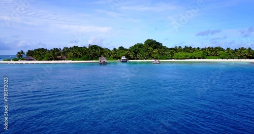 Scenic view of houses on the beach covered with greenery against a turquoise sea on a sunny day