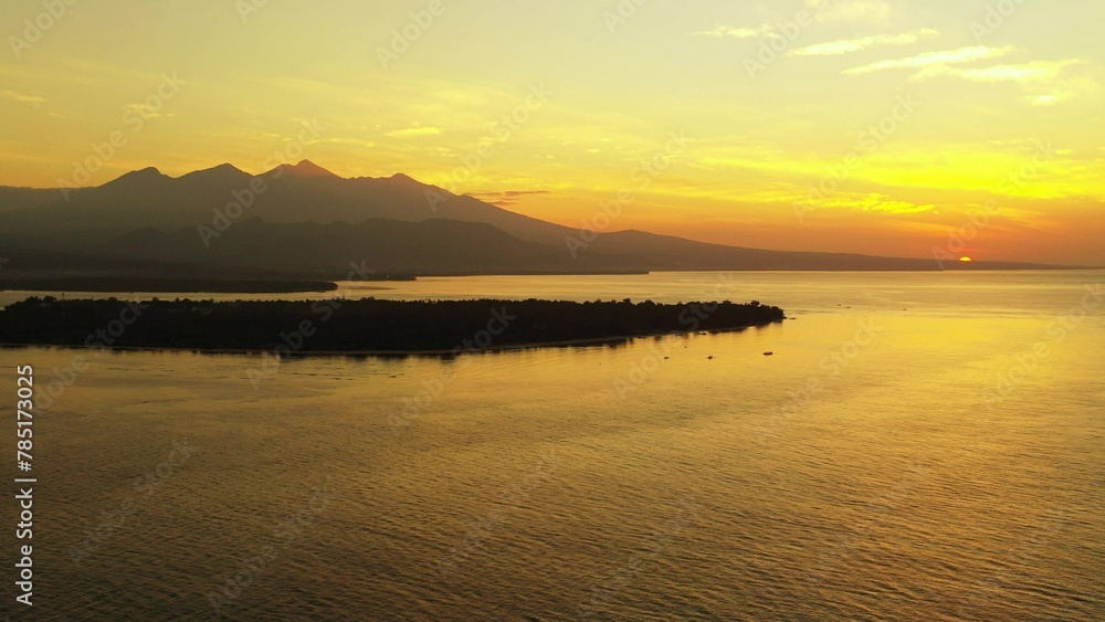 Aerial view of an island covered with greenery against a sea at sunset Aerial view of an island covered with greenery against a sea at sunset