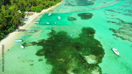 Aerial shot of coral reefs under tranquil water and boats in the sea