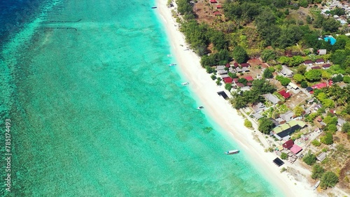 Aerial shot of a paradise island with tropical trees and villas surrounded by turquoise water