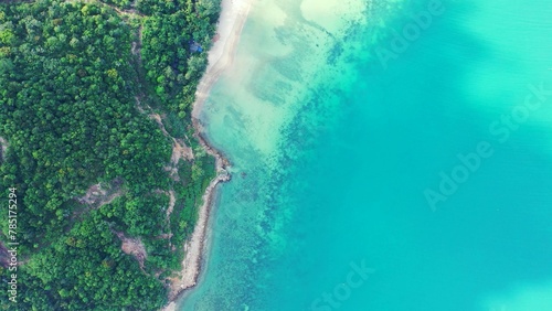 Aerial shot of clear ocean water covering the tropical island's coastline