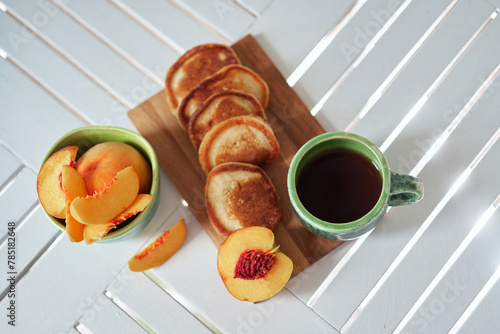 Simple, sweet and Tasty breakfast. Pancake on a wooden plate with peach and coffee in a beautiful ceramic pottery. Weekend morning vibe. High quality photo