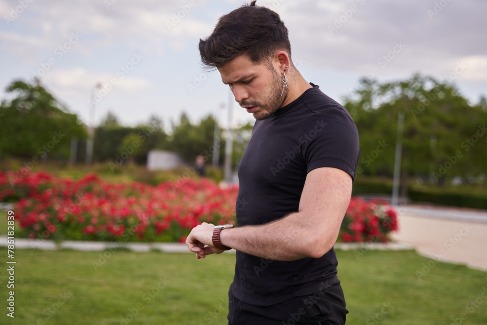latino man in sportswear looks at his smart watch latino man in sportswear looks at his smart watch
