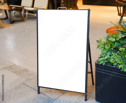 Blank white outdoor advertising stand or sandwich board mock up template. Clear street signage board placed by an outdoor dinning area of a restaurant. Background texture of standee on street. photo