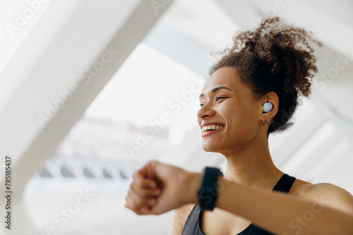 Young woman in sportswear looking at smartwatch and counting calories burned. Healthy life concept  photo