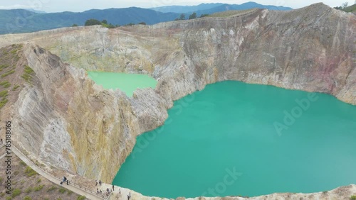 Kelimutu volcano crater on Flores. Two large bodies of water, one of which is green. The other is blue. The scene is serene and peaceful, with the water reflecting the surrounding landscape. photo