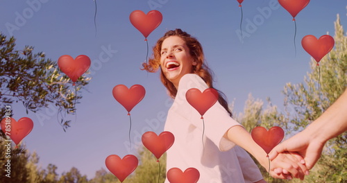 Image of red heart balloons floating over couple in love holding hands in summer