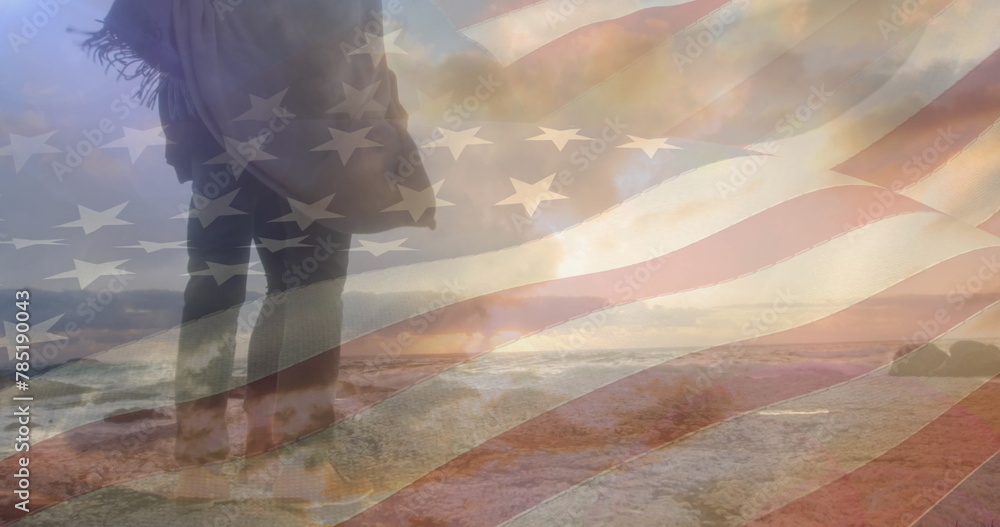 Fototapeta premium Image of flag of united states of america over couple standing on beach