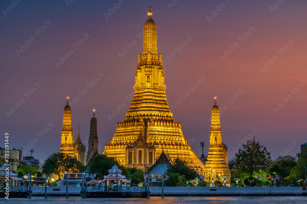 Naklejka premium Wat Arun stupa, a significant landmark of Bangkok, Thailand, stands prominently along the Chao Phraya River, with a beautiful twilight.
